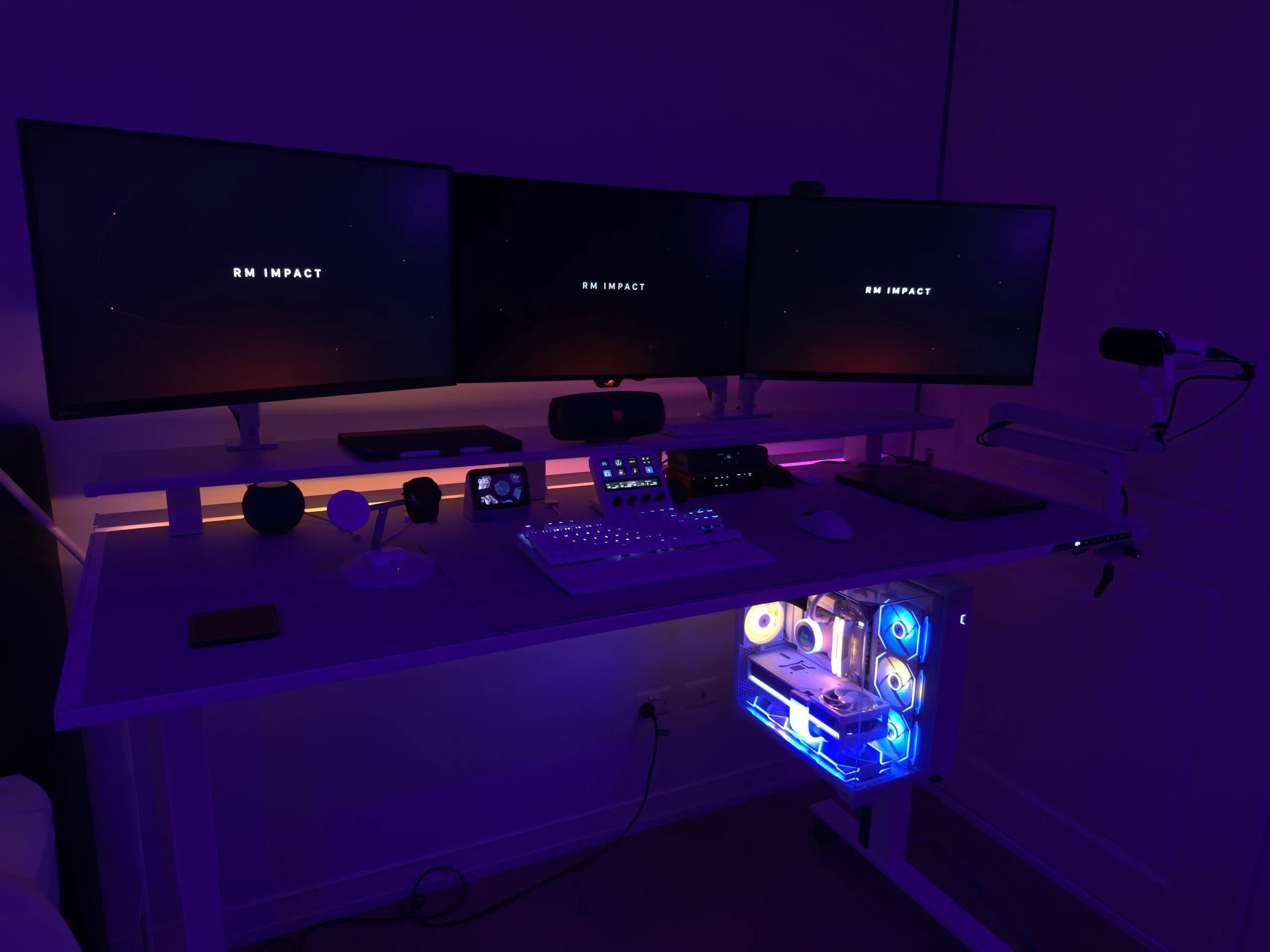 Remy’s desk setup with three monitors, a white custom PC and purple ambient lighting